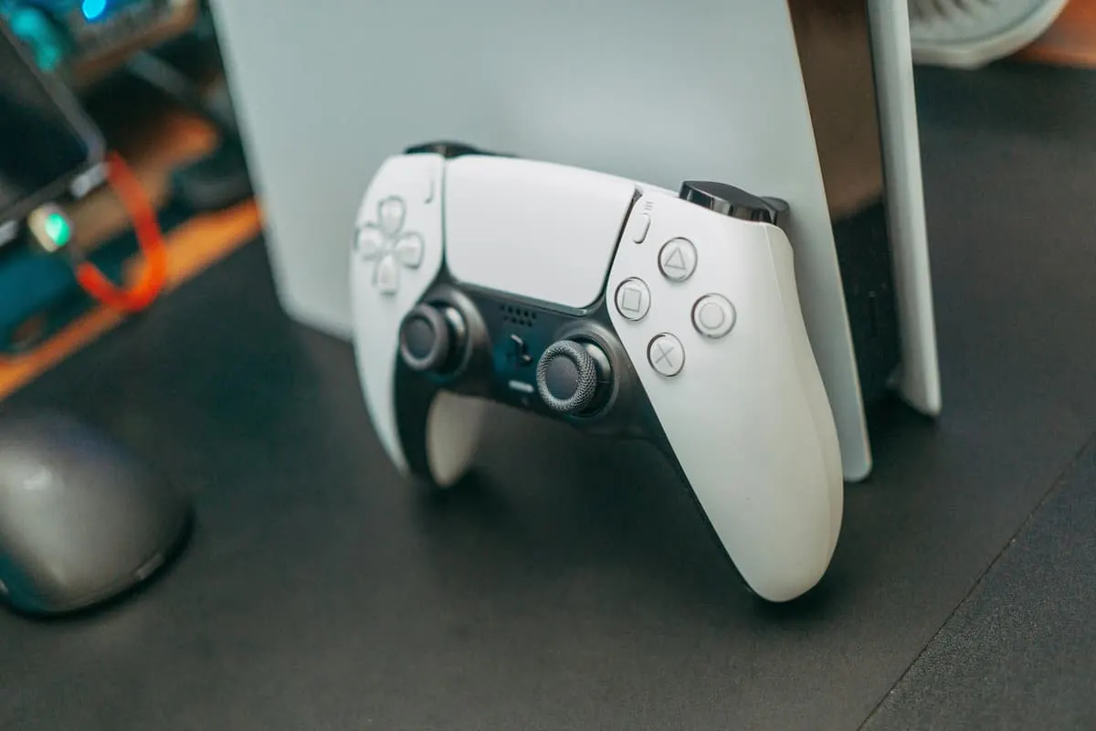 Imagen de un mando de PS5 de color blanco apoyado en una PS5