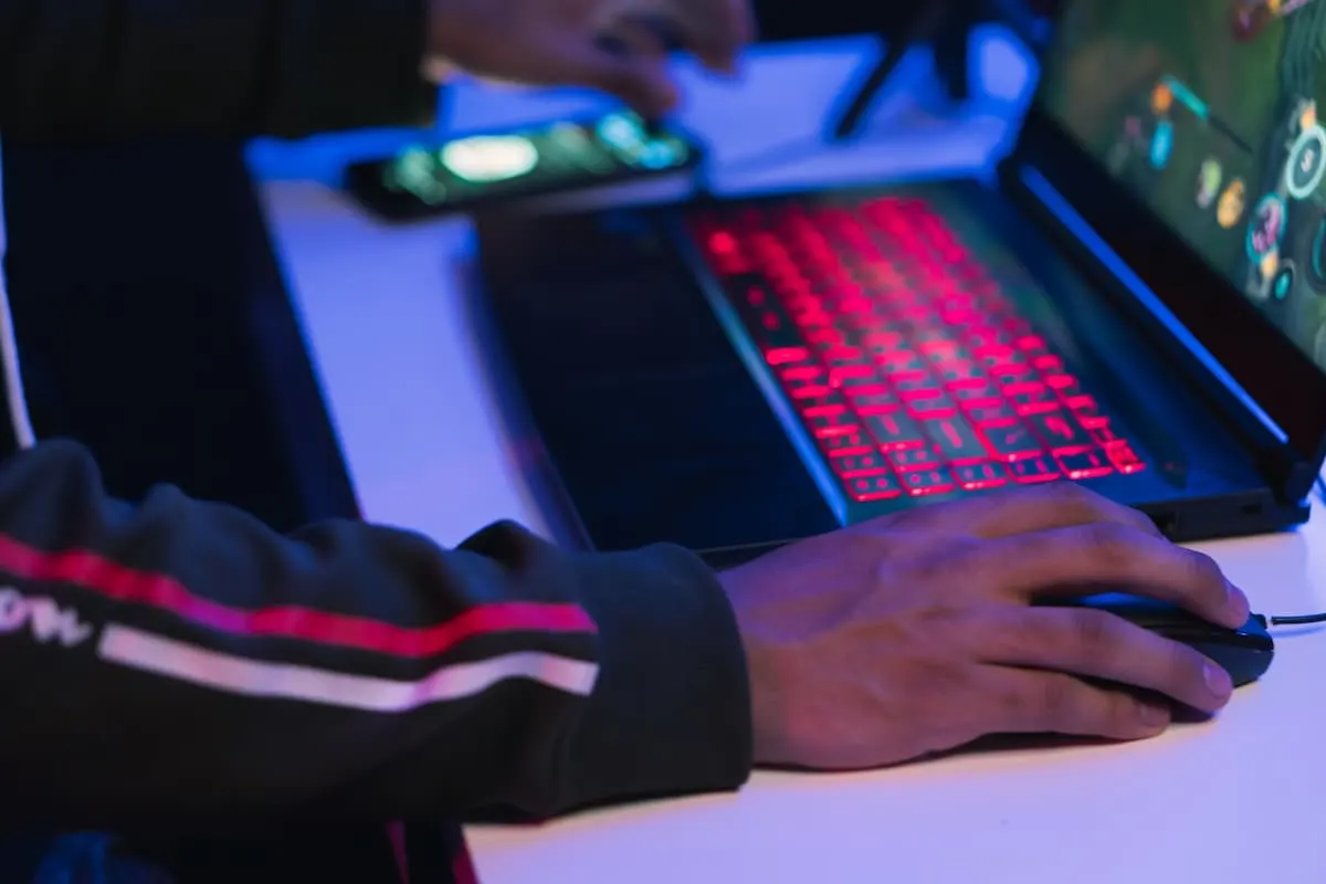 Persona jugando en un portátil gaming con teclado iluminado en rojo