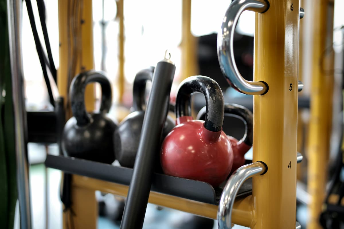 Kettlebells en una estantería de gimnasio, con una estructura metálica amarilla.