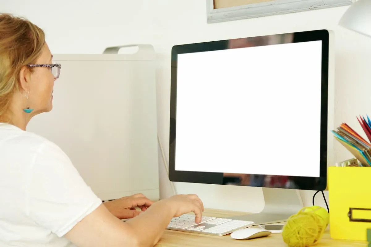 Mujer usando un ordenador de escritorio con la pantalla en blanco.