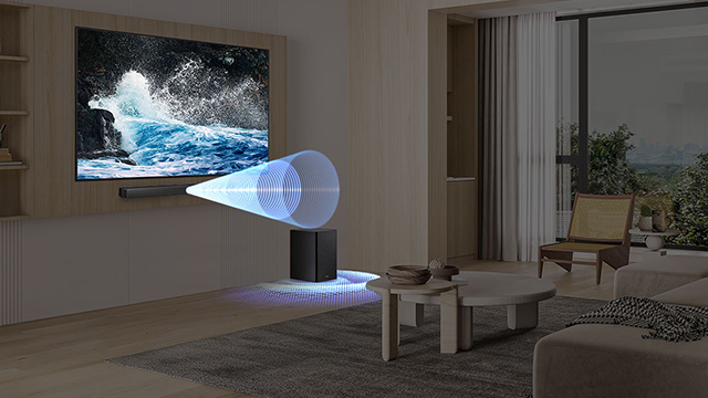 Sala moderna con televisor mostrando olas del mar, barra de sonido y subwoofer emiten efectos visuales de audio envolvente hacia el centro.