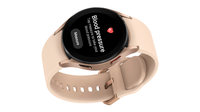 Reloj inteligente con pantalla negra que indica la presión arterial y una correa color crema sobre un fondo blanco.