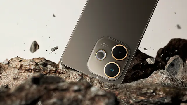 Un teléfono móvil con tres lentes descansa sobre rocas marrones. Fragmentos de roca flotan contra un fondo blanco.