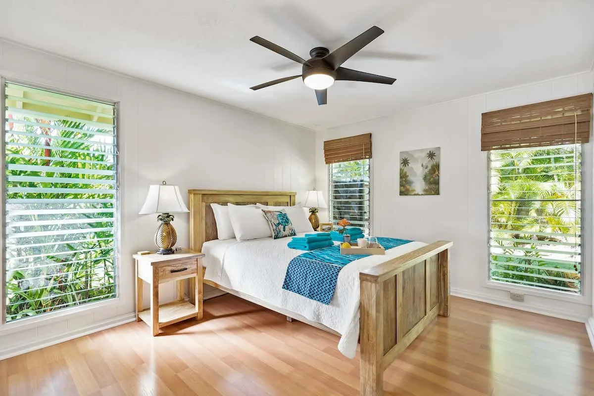 Dormitorio luminoso con ventilador de techo moderno y decoración tropical.