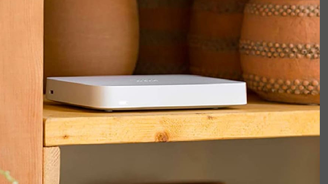 Caja blanca sobre estante de madera clara. Detrás, dos vasijas de cerámica marrón, una con bandas horizontales de puntos.