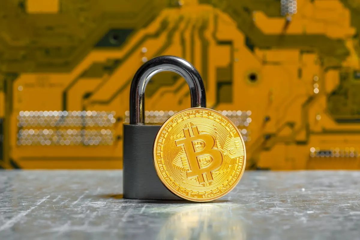 Candado con moneda de Bitcoin frente a un fondo tecnológico, simbolizando seguridad en criptomonedas.