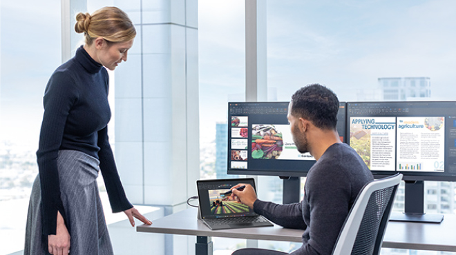 Una mujer usa una tableta con lápiz y un teclado frente a un monitor. El logo de Microsoft está en la esquina superior derecha.