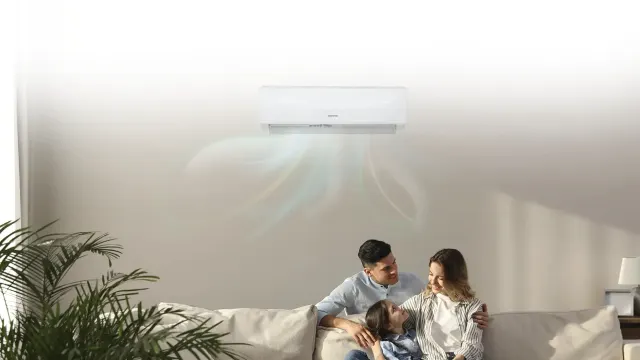 Familia sentada en un sofá con el aire acondicionado encima.