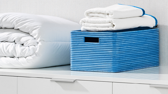 Encimera de un cuarto de lavado con un edredón sintético limpio plegado y una cesta azul con con toallas blancas recién lavadas