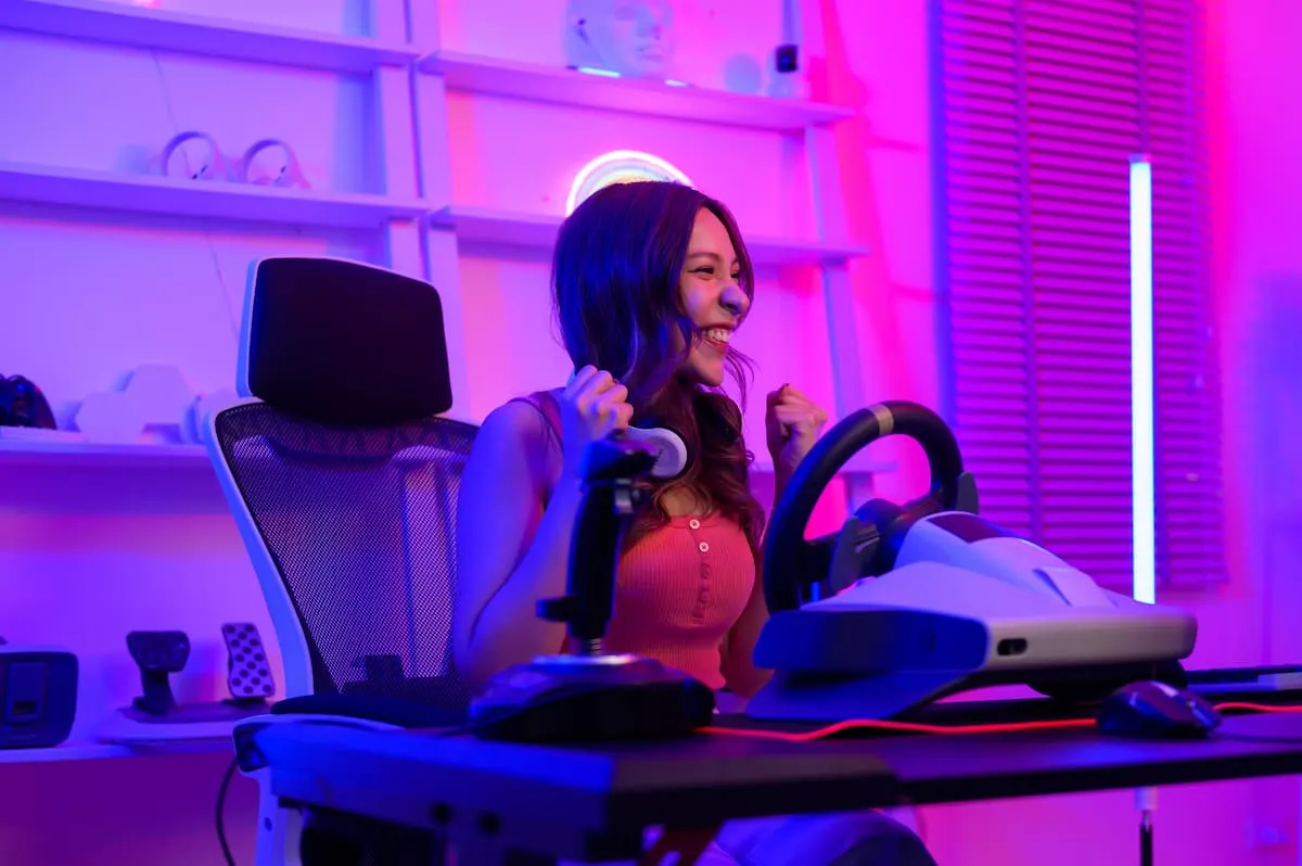 Jugadora entusiasmada usando un volante de carreras en un setup gaming con luces de neón.