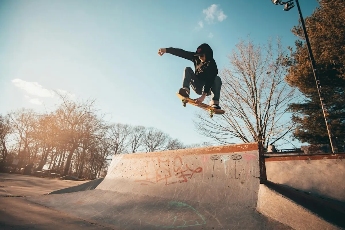 Chico haciendo un salto con el skate en un parque con rampas.