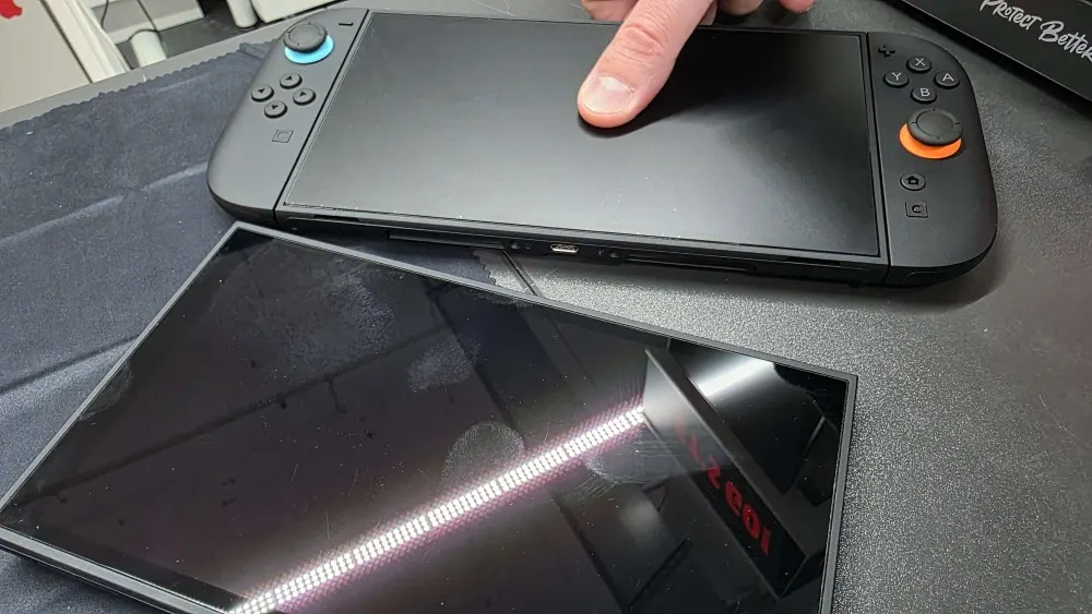 Consola Nintendo Switch 2 con protector mate instalado junto a otra pantalla con reflejos marcados.