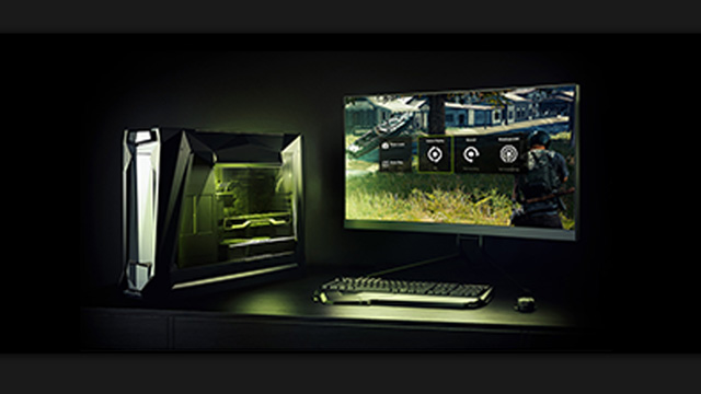 Un ordenador de sobremesa y un monitor muestran un videojuego. El teclado y el ratón están delante del monitor. Fondo oscuro.