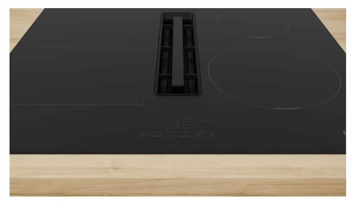Placa de inducción negra con extractor integrado en el centro.