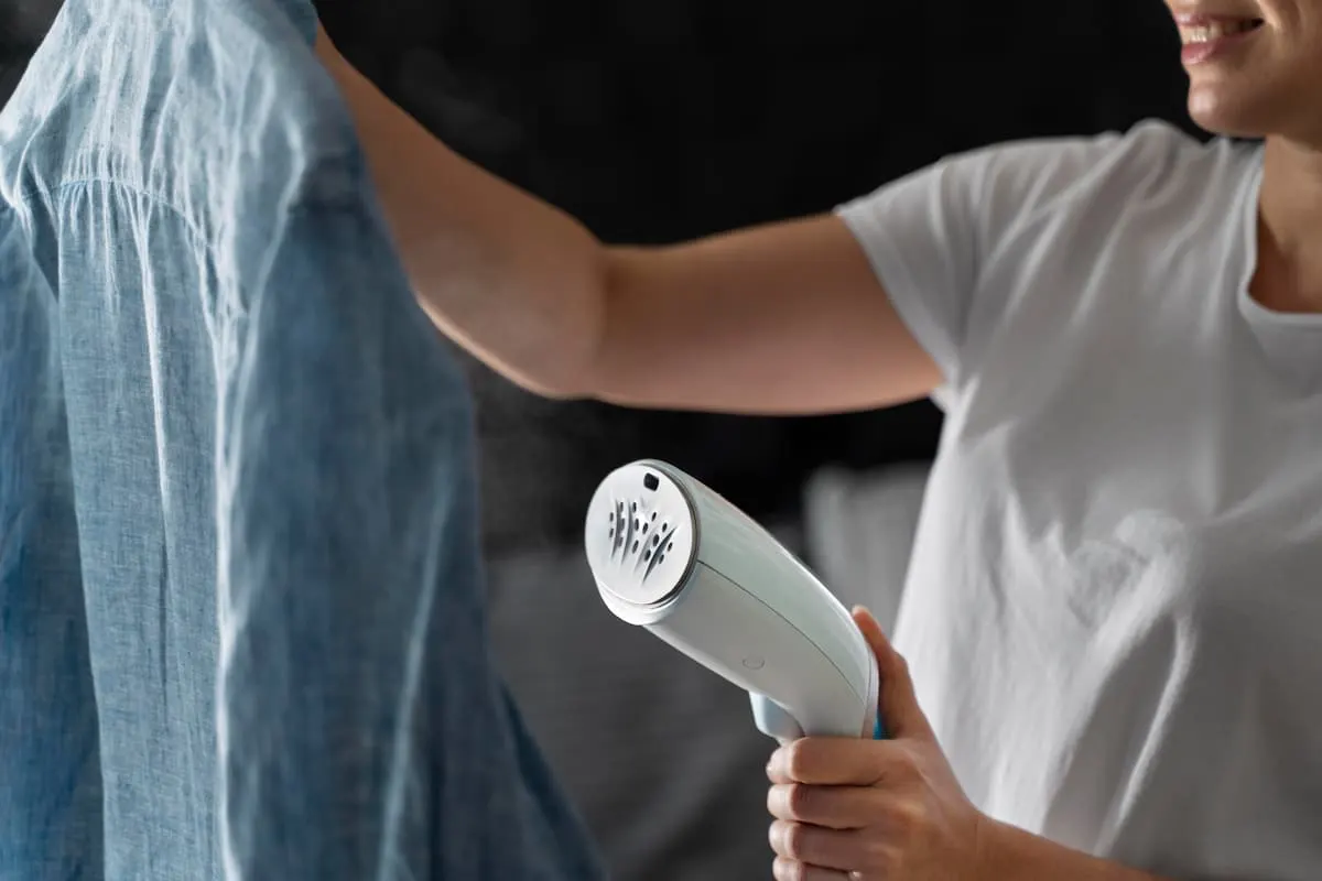 Persona usando una plancha vertical de ropa para quitar arrugas de una camisa.