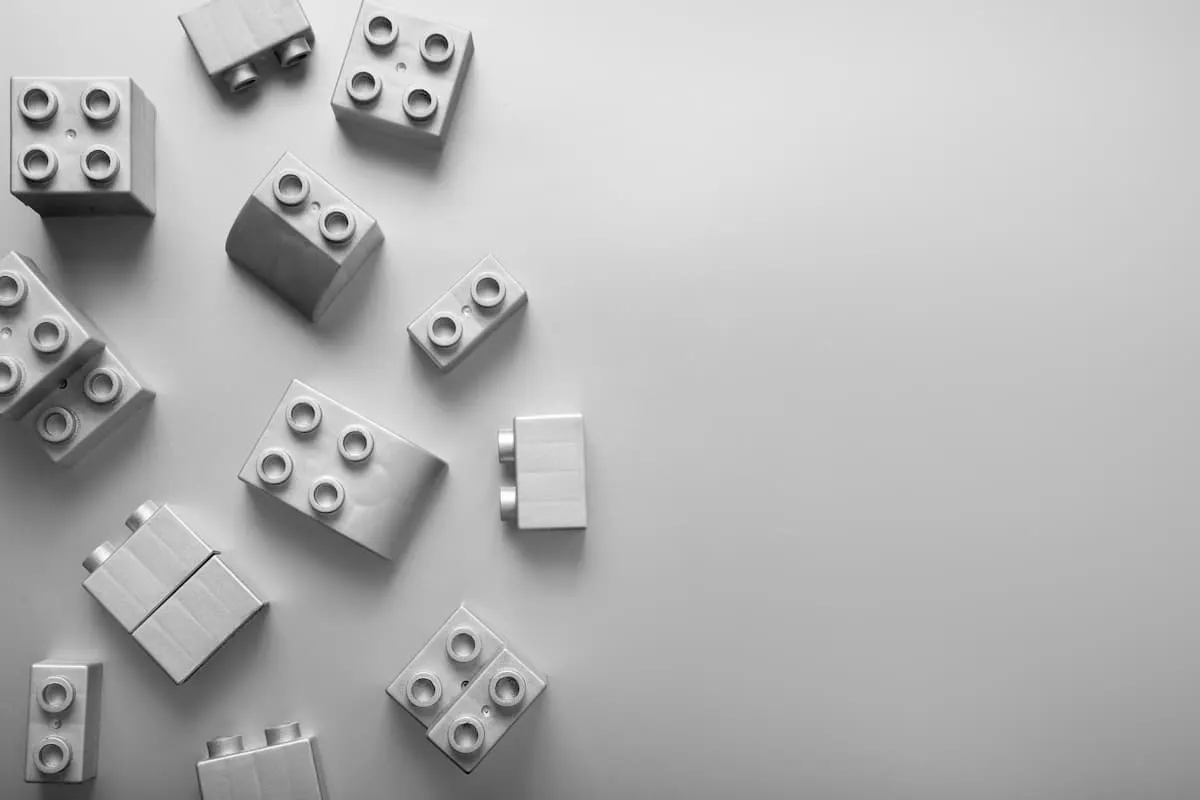 Piezas de LEGO blancas dispersas sobre una superficie gris.