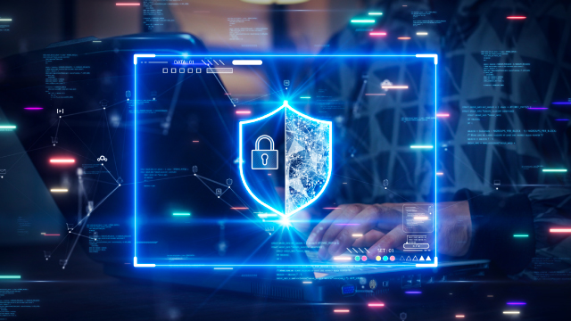 Persona tecleando en un portátil, con un escudo azul brillante y un candado digital superpuesto. Fondo tecnológico con líneas y datos.
