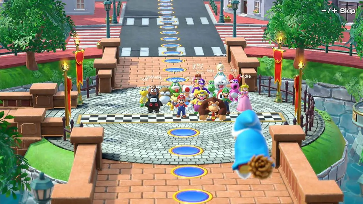 Escena de videojuego con personajes de Mario Bros sobre un puente de ladrillo frente a una calle con edificios.