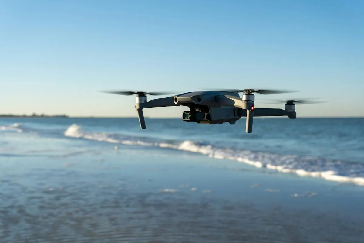 Drone volando sobre la orilla del mar en un día despejado.