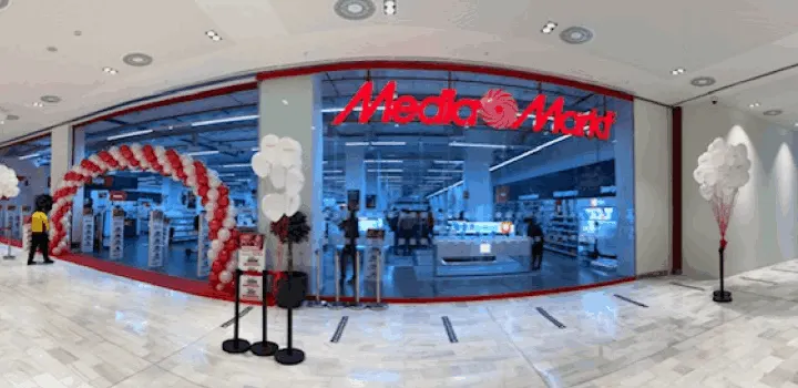 Entrada de tienda Media Markt decorada con arco de globos rojos y blancos. Globos blancos a la derecha y figura entrando a la izquierda.