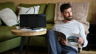 Persona con auriculares trabajando en un portátil en un escritorio. Plantas en el fondo