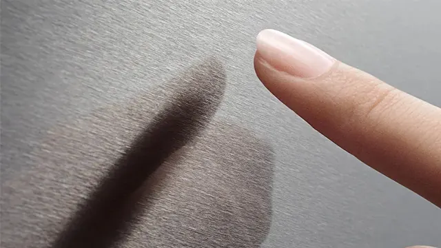Detalle de un dedo tras tocar la superficie de acero inoxidable antihuellas de la puerta