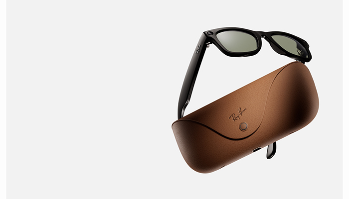 Gafas de montura negra sobre un estuche de cuero marrón con el logo de la marca y un broche metálico, sobre un fondo blanco.