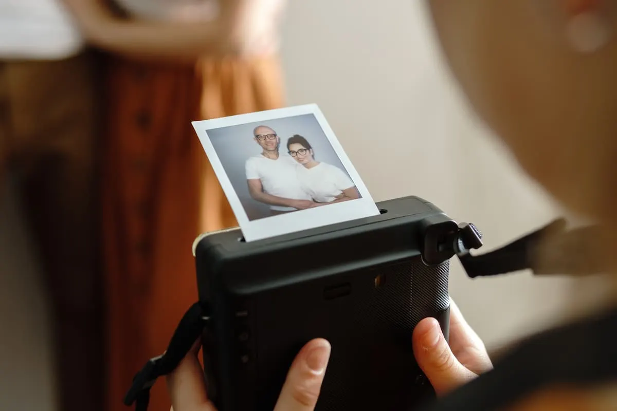 Persona sosteniendo una cámara instantánea mientras se revela una foto polaroid