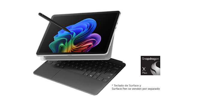 Un portátil gris está abierto sobre una superficie blanca. La pantalla muestra un diseño abstracto con colores del arcoíris.