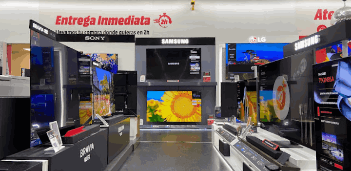 Interior de tienda con televisores de marcas como Sony, Samsung y LG en exhibición. Hay carteles de promoción de entrega inmediata.