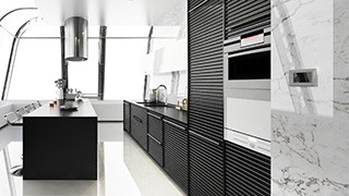 Cocina moderna con isla negra, armarios oscuros y electrodomésticos empotrados en pared blanca con detalles de mármol. Ventana amplia.