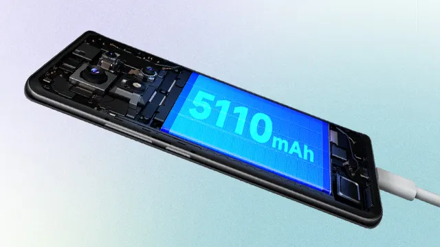 Un teléfono negro muestra una batería azul de 5110 mAh y componentes internos. Un cable blanco se conecta al lado derecho.