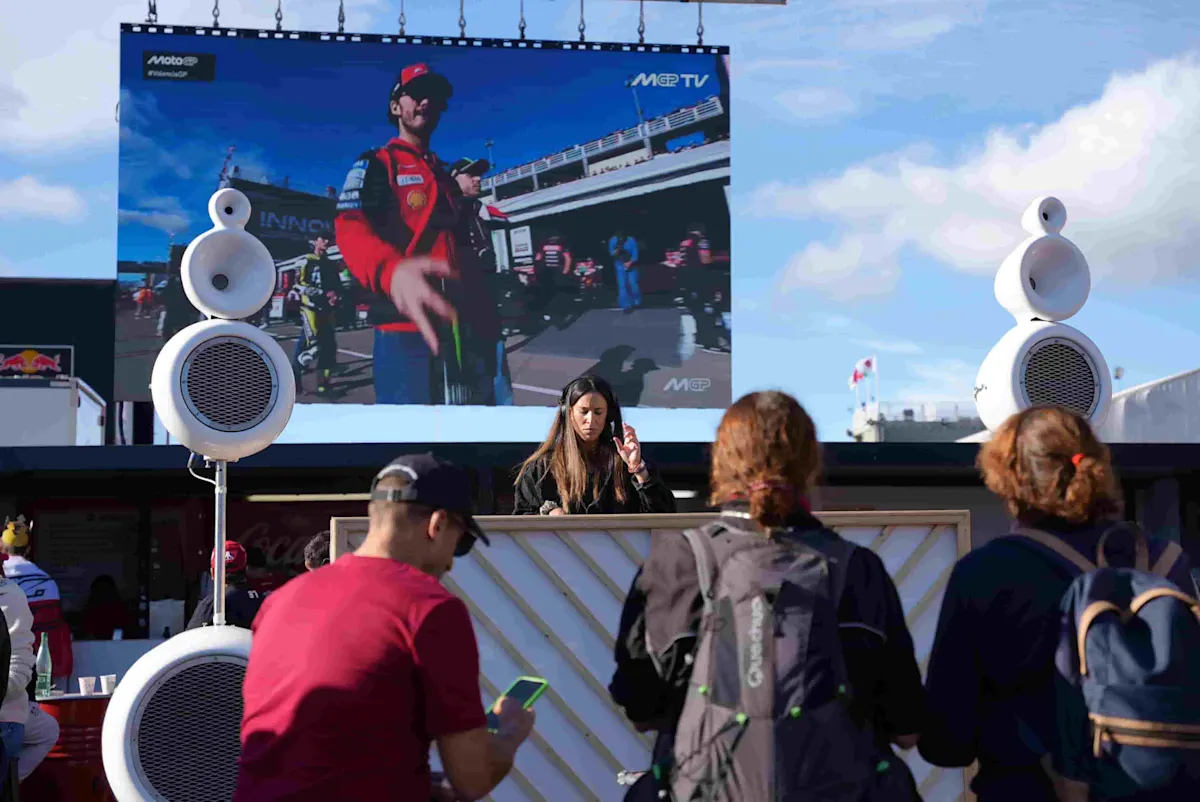 DJ pinchando en la Fan Zone del MotoGP de Valencia con gran pantalla y público frente al escenario.