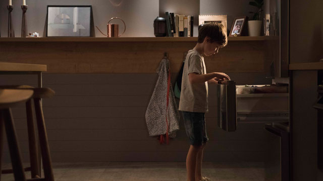 Niño abriendo un cajón del frigorífico en una cocina.