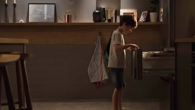 Niño abriendo un cajón del frigorífico en una cocina.