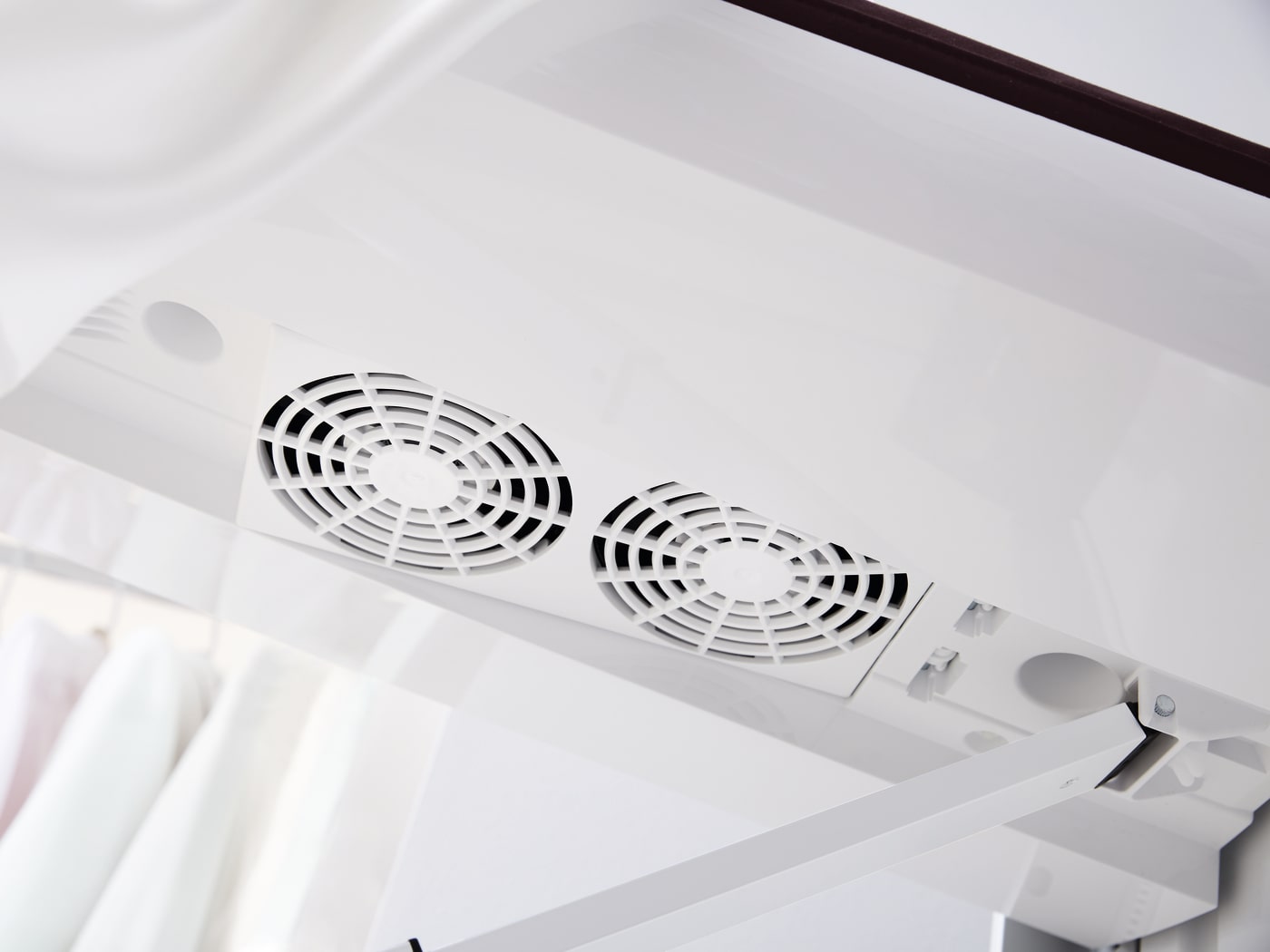 Vista desde abajo de un deshidratador blanco con dos ventiladores redondos negros y blancos. Se ven cortinas blancas.
