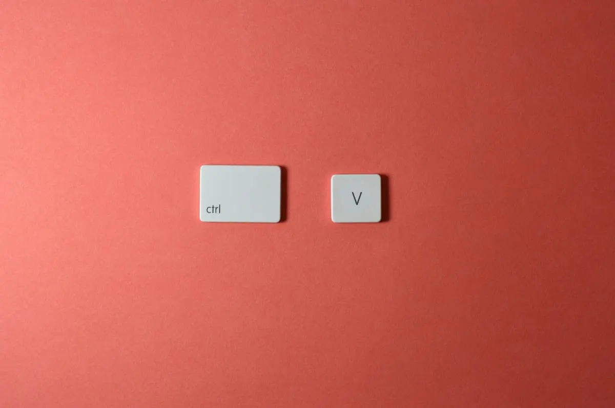 Teclas "Ctrl" y "V" sobre fondo rojo, representando el comando de pegar.