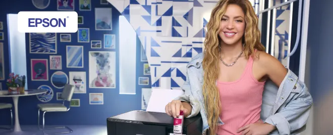 Impresora Epson en escritorio con botella de tinta magenta, en una habitación decorada con cuadros azules.