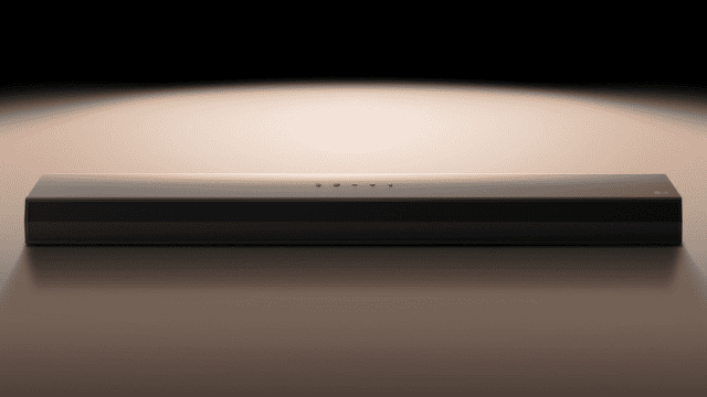 Una barra rectangular negra con pequeños orificios en la parte superior está sobre una superficie lisa. El fondo es oscuro.