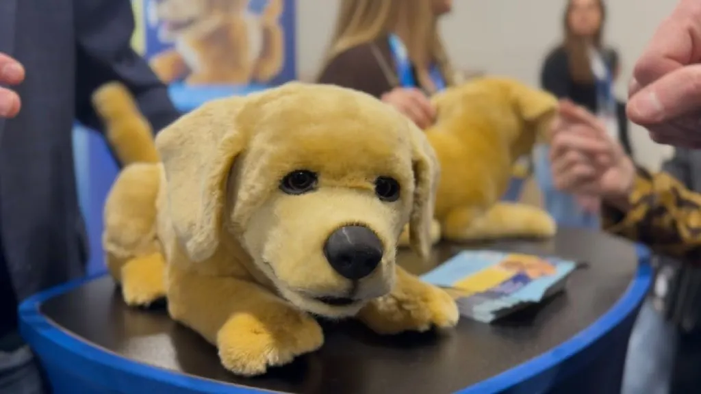 Perro robótico de peluche sobre una mesa en una feria tech.
