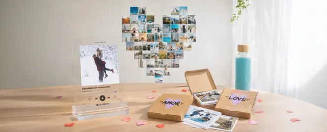 Mesa con regalos personalizados: placa con foto romántica, cajas de fotos “AMOR” y “LOVE” y mural de fotos en forma de corazón.