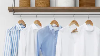 Camisas y blusas de colores azules y blancos, perfectamente planchadas y colgadas en orden