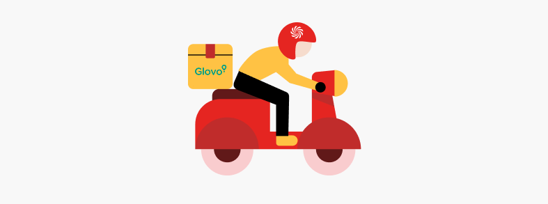 Un repartidor con casco rojo conduce una moto roja. Lleva una caja amarilla de Glovo en la parte de atrás.