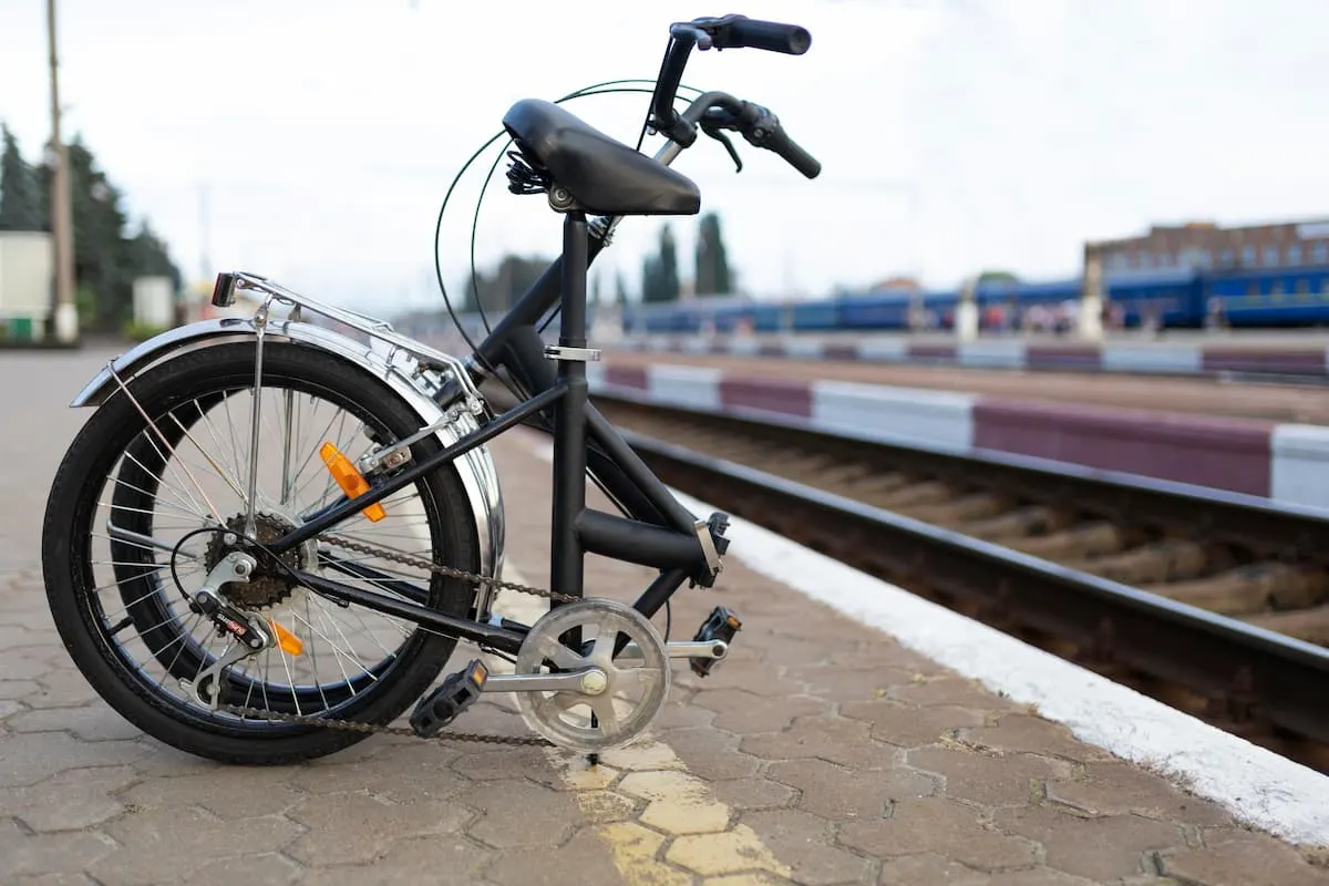 Bicicleta plegable negra estacionada en el andén de una estación de tren.