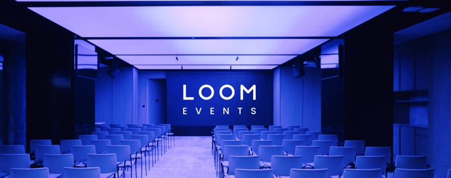 Sala de eventos con sillas azules en filas y pantalla mostrando 'LOOM EVENTS' con iluminación azul y púrpura ambiente.