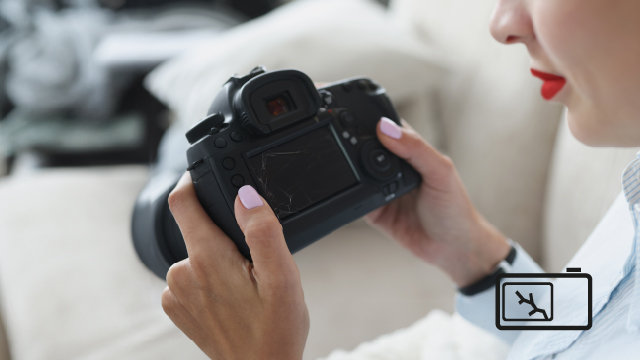 Una mujer sostiene una cámara negra con las dos manos. Lleva una camisa blanca y un reloj oscuro. Fondo blanco.