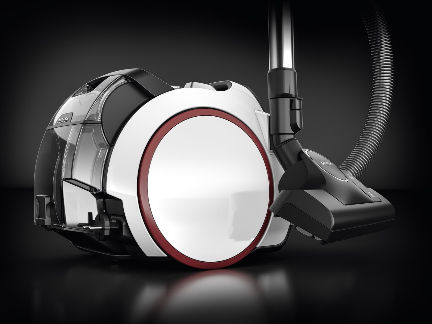 Aspiradora blanca y negra con detalles rojos, manguera corrugada y tanque transparente sobre fondo negro.