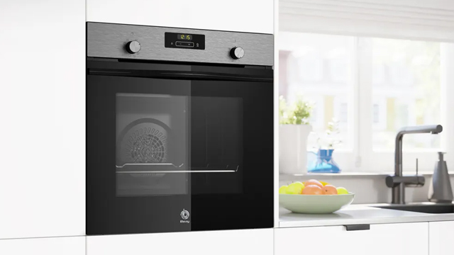 Horno multifunción en color negro y acero, de Balay, instalado en alto junto a una encimera y una gran ventana