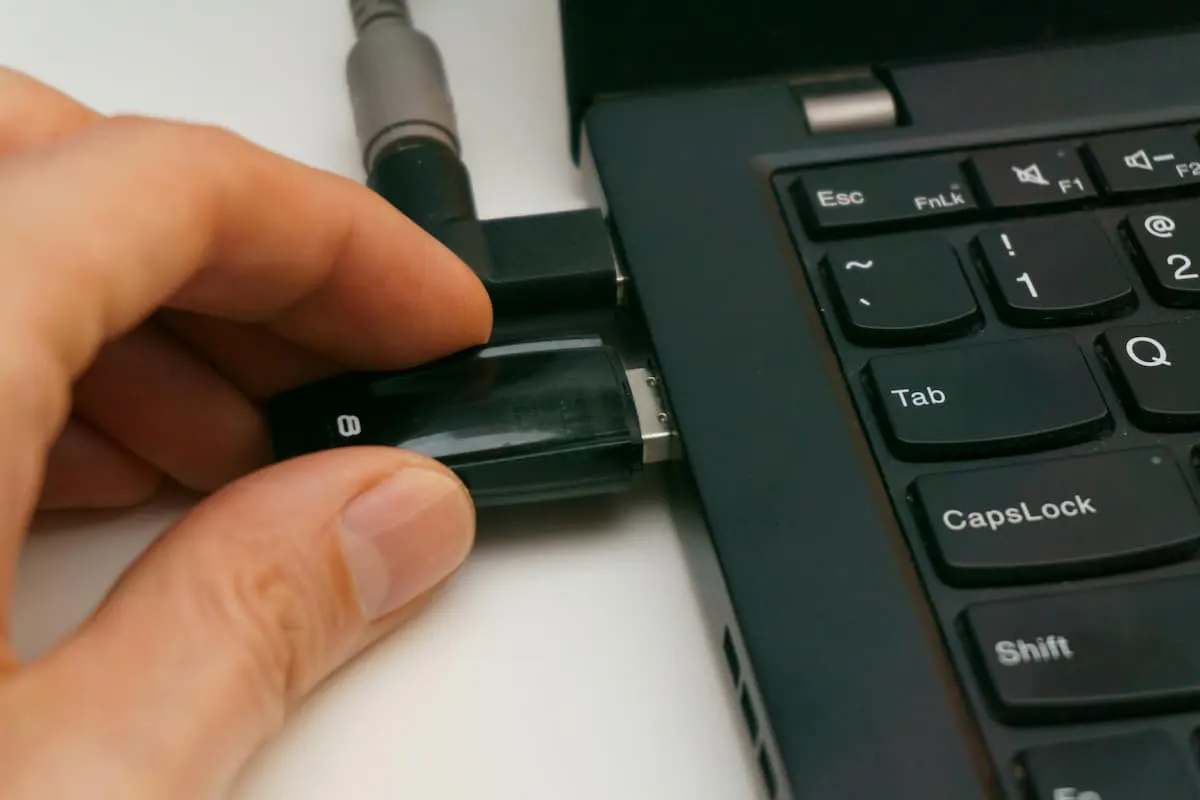 Persona conectando una memoria USB a un portátil.