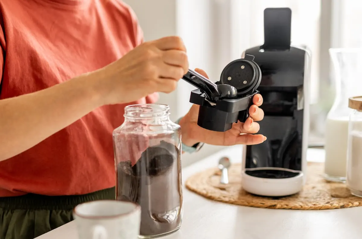 Mujer preparando café con cafetera Dolce Gusto de cápsulas en cocina